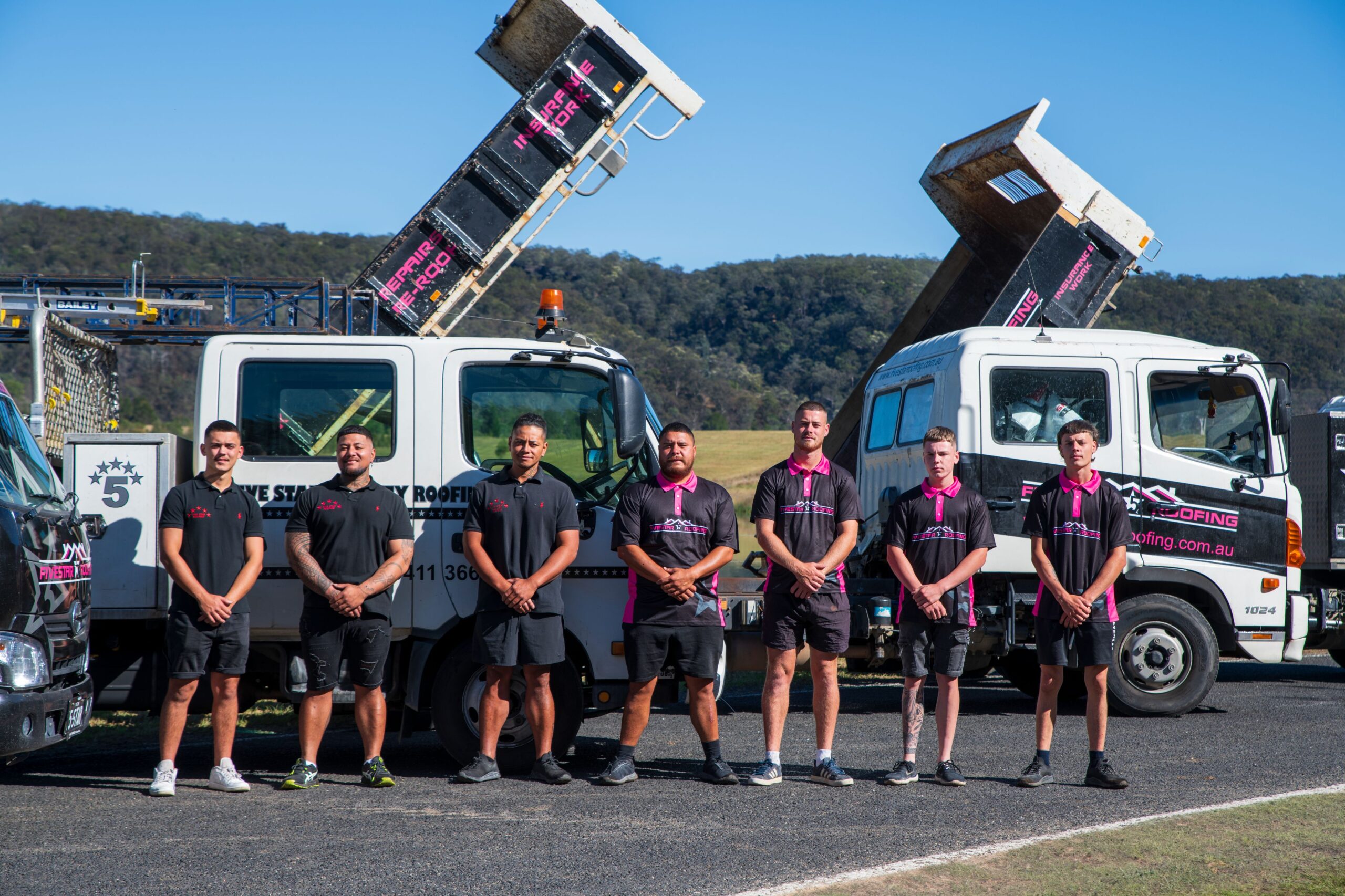 Commercial roof repair team from Five Star Roofing standing in front of branded service trucks, ready for roofing projects in Australia.