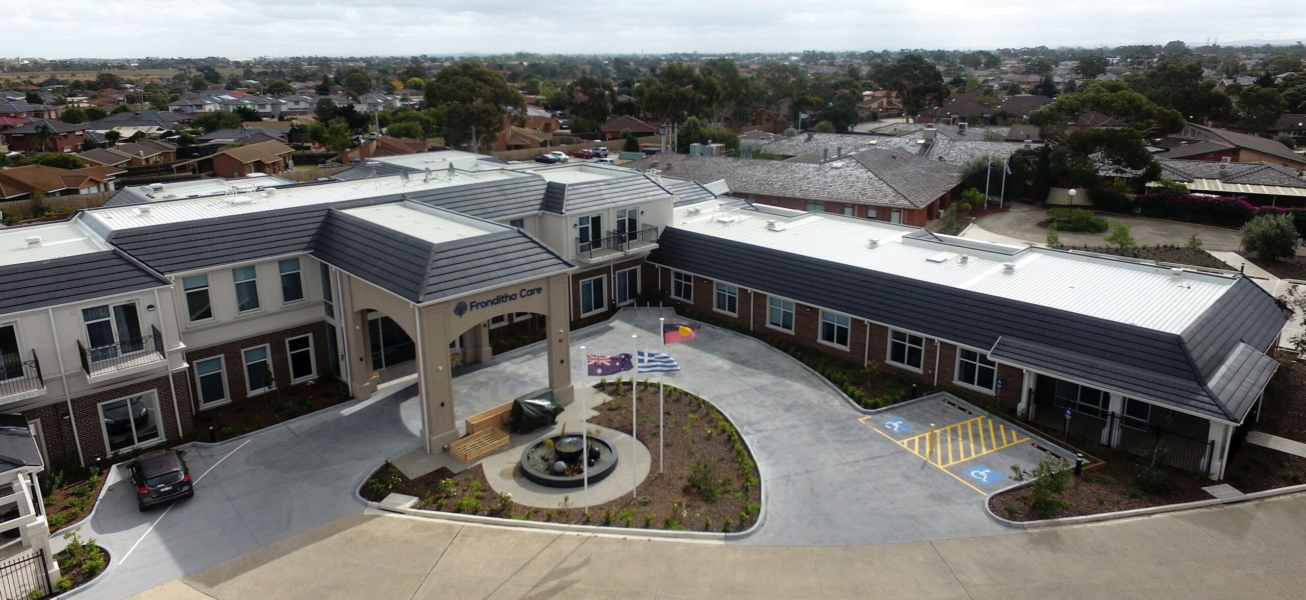 Commercial roof replacement completed on a large aged care facility in Australia, featuring new metal roofing and tiled parapets.