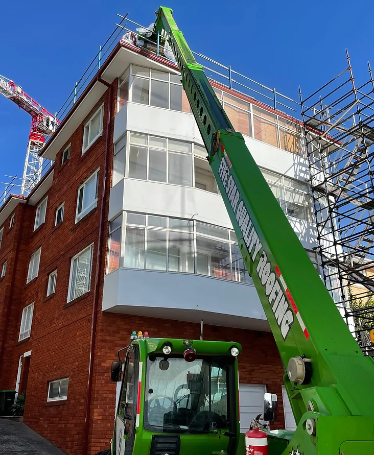 Roof repair on multi-storey apartment building in Sydney using crane and scaffolding for high-access roofing work.