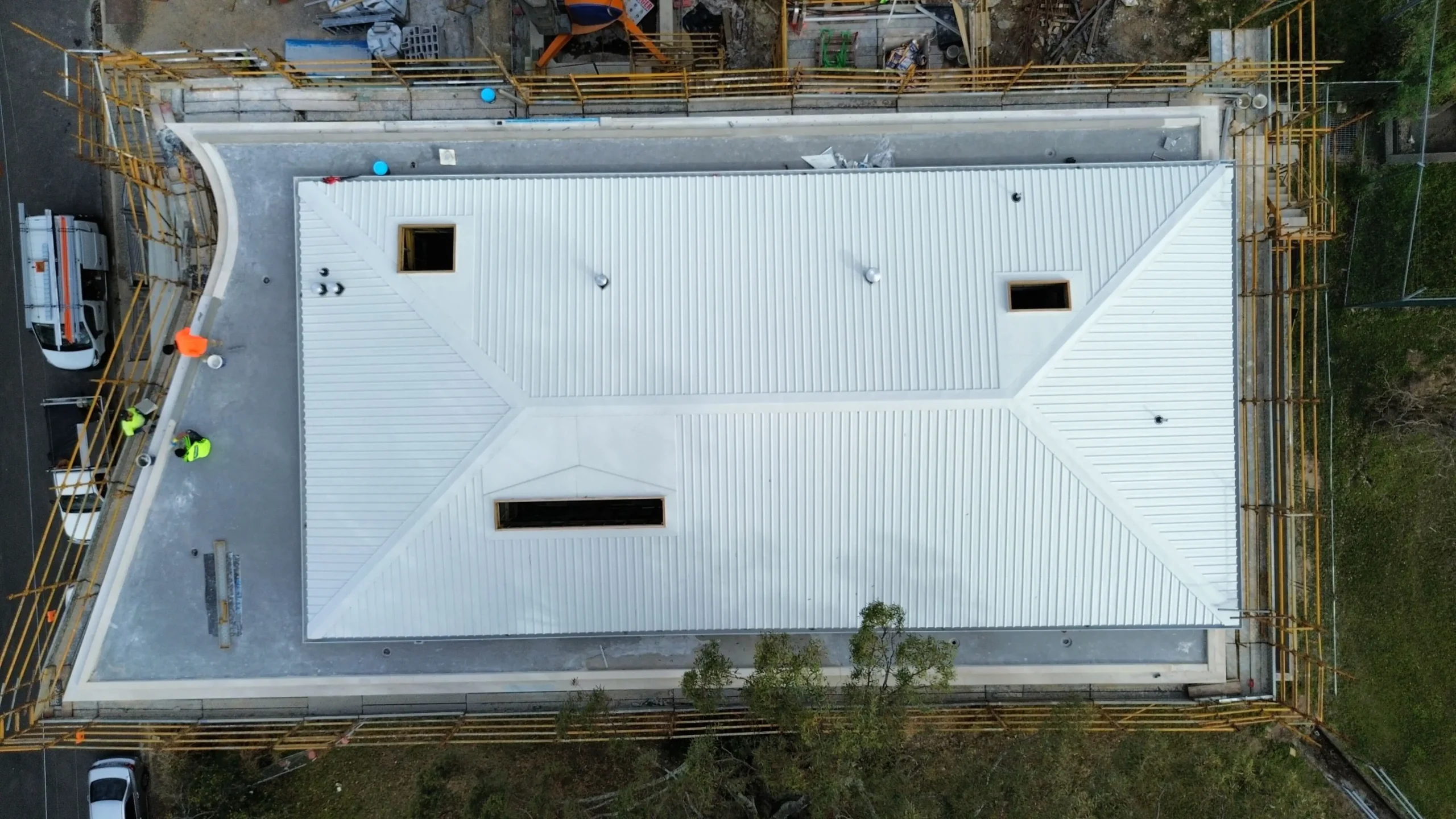 Aerial of workers repairing metal roof on construction site.