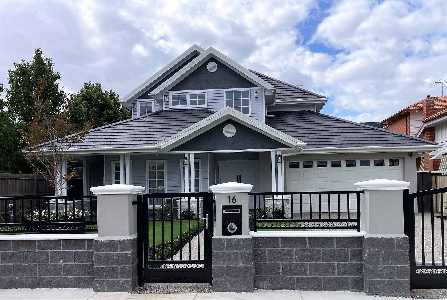 Modern gray house with restored black tile roof, garage.